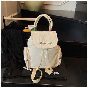 Detail of cream backpack showing colorful MeaRey embroidery and corded handles