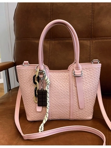 Sac bandoulière rose à texture tressée et breloque chocolat sur fond en cuir brun