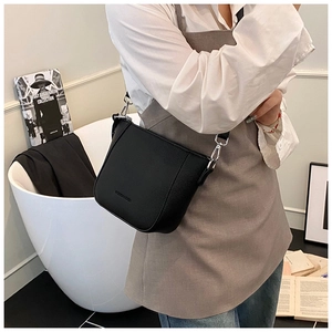 Détail du sac seau en cuir noir grainé avec boucles métalliques argentées et bandoulière