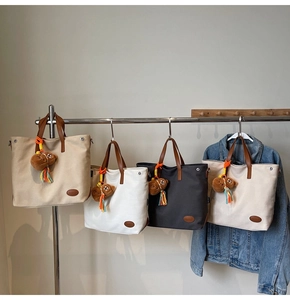 Detail of canvas tote bags with leather handles and cute plush bear charms in 4 colors
