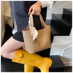 Detail of khaki lychee grain leather tote bag with elegant heart print silk scarf handle