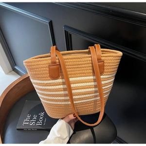 Detailed close-up of woven tote bag with brown leather handles on a black chair