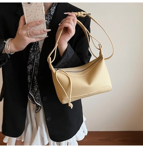 Close-up of beige lychee pattern leather crossbody bag worn with a stylish blazer outfit