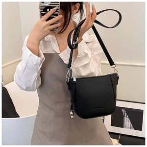 Détail du sac seau noir en cuir grainé avec breloque chat argentée et bandoulière