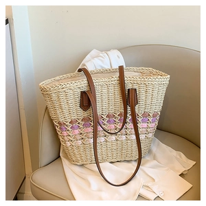 Détail du sac cabas en paille tissée avec rayures colorées sur un fauteuil en cuir
