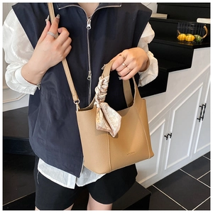 Detail of light tan bucket bag with lychee texture and silk scarf handle accent