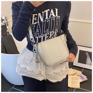 Détail du sac seau en cuir argenté grainé avec breloque métallique sur mannequin