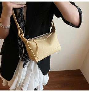 Close-up of beige lychee pattern leather handbag with matching shoulder strap on a model