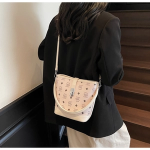 Detail of beige leather bucket bag featuring cartoon bear print and magnetic flap closure