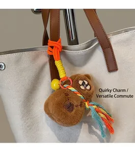Detail of cute brown plush bear charm with orange rope and bell on white canvas tote bag