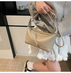 Close-up of beige lychee texture leather shoulder bag with sleek metal zipper and tassel