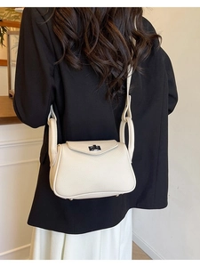 Minimalist beige pebble leather crossbody bag with silver buckle worn on a shoulder