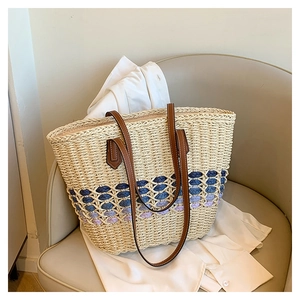 Détail du sac cabas en paille tissé avec motifs de vagues bleues et anses en cuir