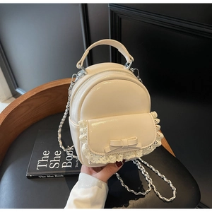 Detail of cream backpack with lace trim, bow decoration and silver chain strap