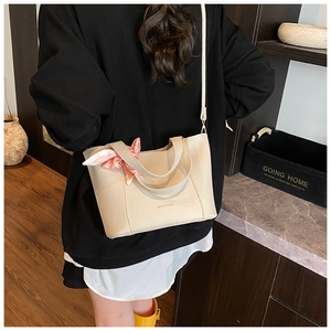 Detail view of off-white lychee grain leather bucket bag with silk scarf and shoulder strap