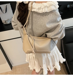 Detailed macro view of the cream lychee grain leather texture and zipper of the shoulder bag