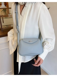 Light blue pebbled leather shoulder bag with silver turn-lock clasp shown on a model