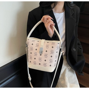 Detail of two-tone bucket bag featuring embossed cat patterns and gold twist lock closure
