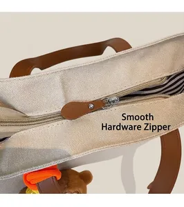 Detail of smooth silver zipper with brown leather pull on canvas tote bag with striped lining