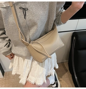 Close-up of beige lychee grain leather shoulder bag with stylish knotted zipper detail