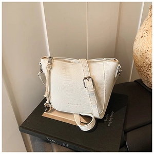 Détail du sac seau blanc à motif litchi avec breloque cœur et bandoulière à boucle