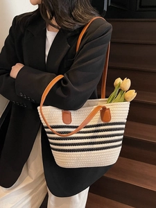 Chic black and white striped woven tote bag with brown leather straps for summer beach use