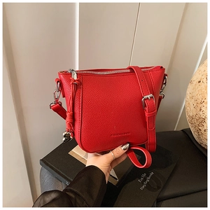 Gros plan sur la texture cuir rouge du sac seau avec pendentif cœur et zip argenté