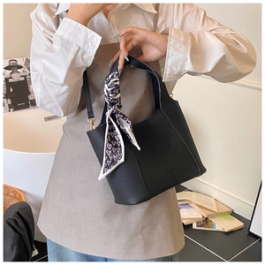 Detail of black pebbled leather bucket bag with a heart-patterned silk scarf on the handle