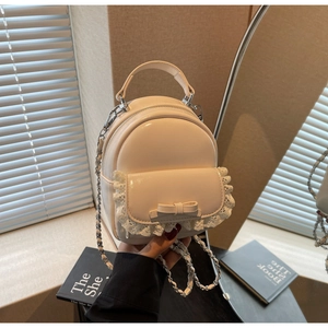 Close-up of cream mini backpack featuring lace trim, bow detail and silver chain straps