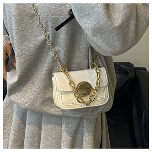 Detailed view of white crocodile pattern girl bag with round gold lock and chain