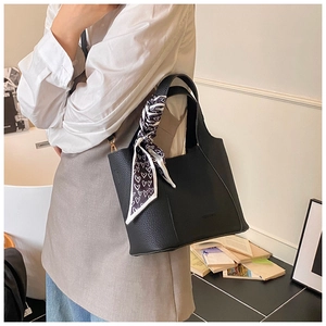 Close-up of black litchi pattern leather bucket bag with decorative heart print silk scarf