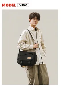 Outdoor street photo of a large black canvas messenger bag with durable double buckle closure