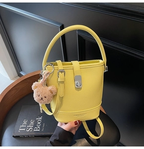 Detail of yellow pebbled leather bucket bag with silver buckle and bear charm