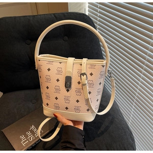 Detail of light beige bucket bag with printed pattern and gold metal clasp closure