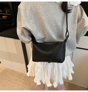 Detail of black lychee grain mini crossbody bag worn by a model in casual home setting