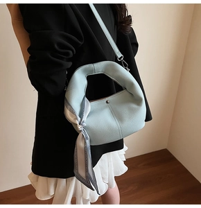 Detail der hellblauen sichelförmigen Handtasche aus Leder mit elegantem Seidenschal-Griff