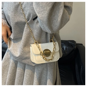 Detail of white crocodile pattern texture and golden round lock on kids shoulder bag