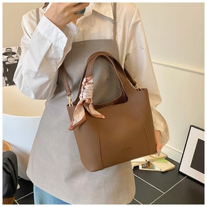 Close-up of brown litchi leather bucket bag with decorative heart-pattern silk scarf