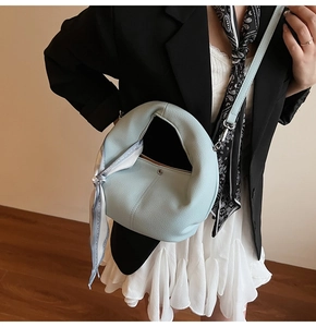 Hellblaue Handtasche aus Leder mit Seidenschal an einem modernen City-Mode-Modell