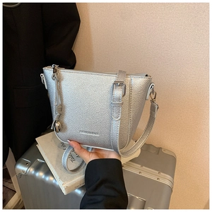 Détail du sac seau argenté métallisé avec texture grainée et pendentif boule métallique