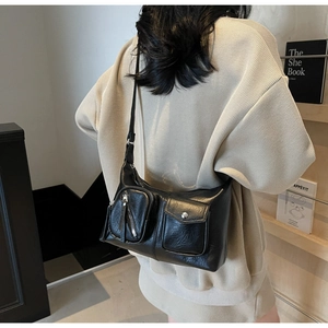 Close-up of black leather crossbody bag featuring dual functional front pockets and straps