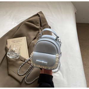 Detail of light blue mini backpack with lace edge and leather bow accent on front pocket