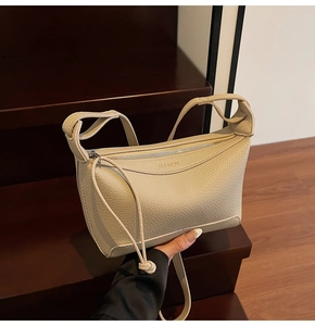 Detailed view of cream pebble leather crossbody bag on wooden steps showing texture
