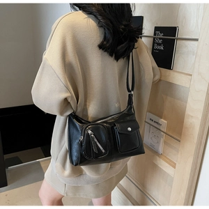 Black vintage shoulder bag shown on model featuring multi-pocket design and matte finish
