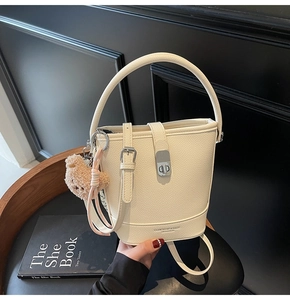 Detail of off-white lychee texture bucket bag with bear charm and brand logo