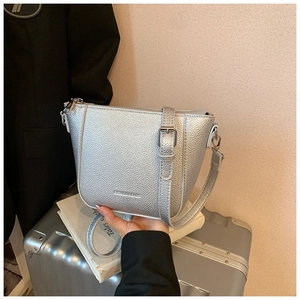Gros plan du sac seau argenté en cuir grainé avec bandoulière et texture détaillée