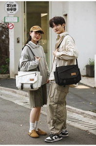 Outdoor shot of men's utility messenger bags in ivory and black with dual buckle design