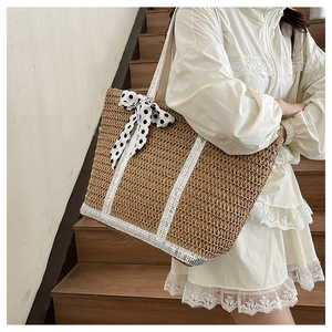 Détail d'un sac cabas en paille avec sangles à paillettes et ruban à pois porté