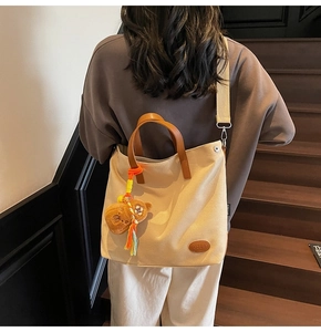 Detail of beige canvas tote bag with brown leather handles and cute bear plush charm