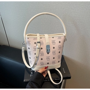 Detail of monogrammed bucket bag with metal lock and curved handle on a black book